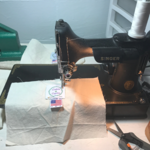 Singer sewing machine with a white piece of fabric with two labels sewn on.