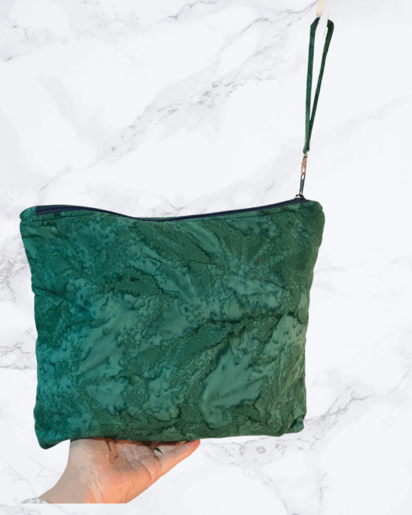 Eleven by thirteen inch project bag handcrafted with a dark green batik fabric. Has a zipper closure with an accessible handle attached to the zipper.