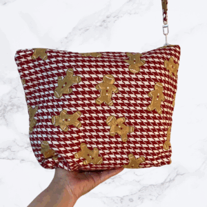 Eleven by thirteen inch project bag handcrafted with gingerbread figures on a red and white checked background. Has a zipper closure with an accessible handle attached to the zipper.