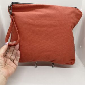 eleven by thirteen inch project bag handcrafted with burnt orange upcycled fabric. Zipper is included with an accessbile handle which makes it easier to open and closer. The lining is a light color which helps to see the interior more easily.